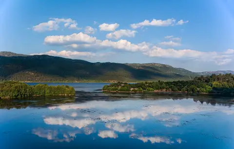 Kovada Gölü'nün bulutları yansıtan durgun suyu ve ormanlı kıyıları