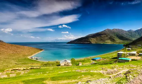 Van Gölü Deveboynu Yarımadası Milli Parkı'nda yeşil çayırlarla çevrili turkuaz koy, kumsal ve arkadaki dağlık yarımada