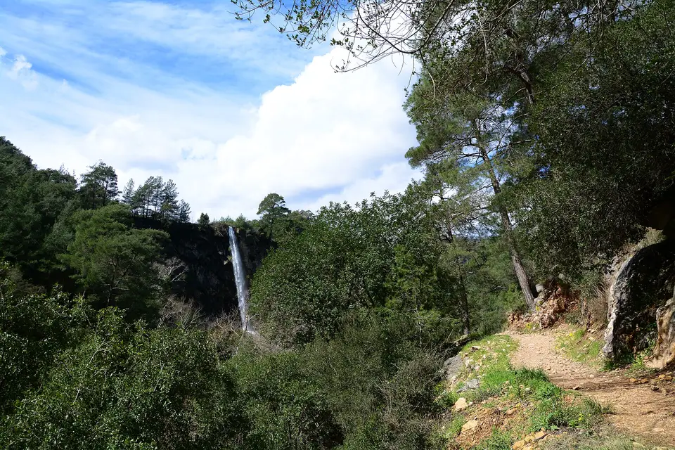 Kayalık kanyon duvarından ormanın içine dökülen ince şelale ve yürüyüş patikası