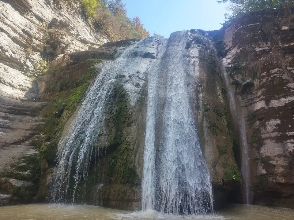 Kireçtaşı kaya duvarından iki kol hâlinde dökülen şelale