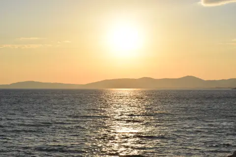 Gümüldür'de denizin üzerinde batan güneş ve karşıdaki dağlar
