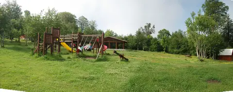 Kuzuyayla Tabiat Parkı'nda çayır üzerindeki çocuk oyun alanı ve ağaçlar