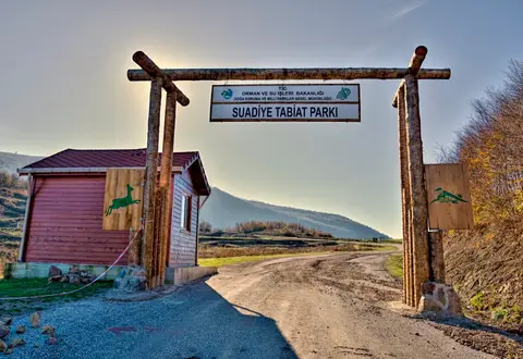 Suadiye Tabiat Parkı girişinde ahşap kapı, park tabelası ve küçük bekçi kulübesi