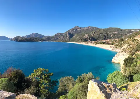 Ölüdeniz'in uzun kumsalı, turkuaz denizi ve ardındaki dağlar