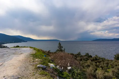 Bafa Gölü kıyısında toprak yol, makilik ve bulutlu gökyüzü